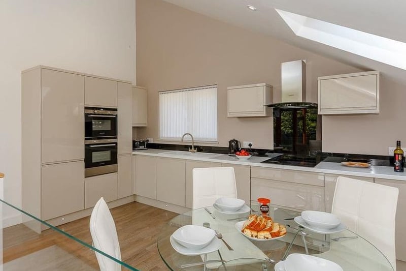 The kitchen area has a double electric oven, induction hob, microwave, fridge/freezer, dishwasher and washer/dryer.