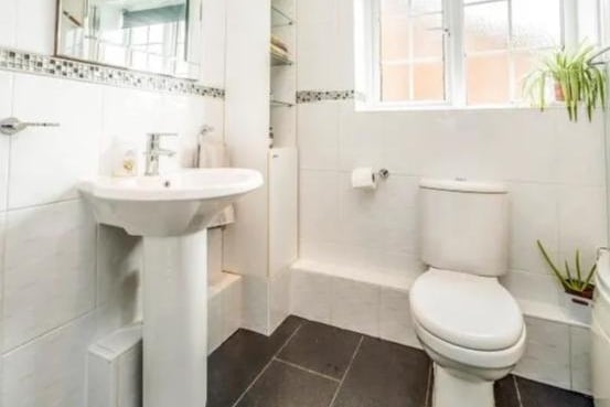 Fully tiled wall & floor shower room in white with shower above bath. Heated towel rail and double glazed window.