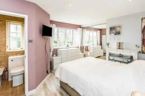 Spacious master bedroom with fitted wardrobes, walk in wardrobe, laminated flooring, double glazed window, central heating radiator and door leading to en-suite