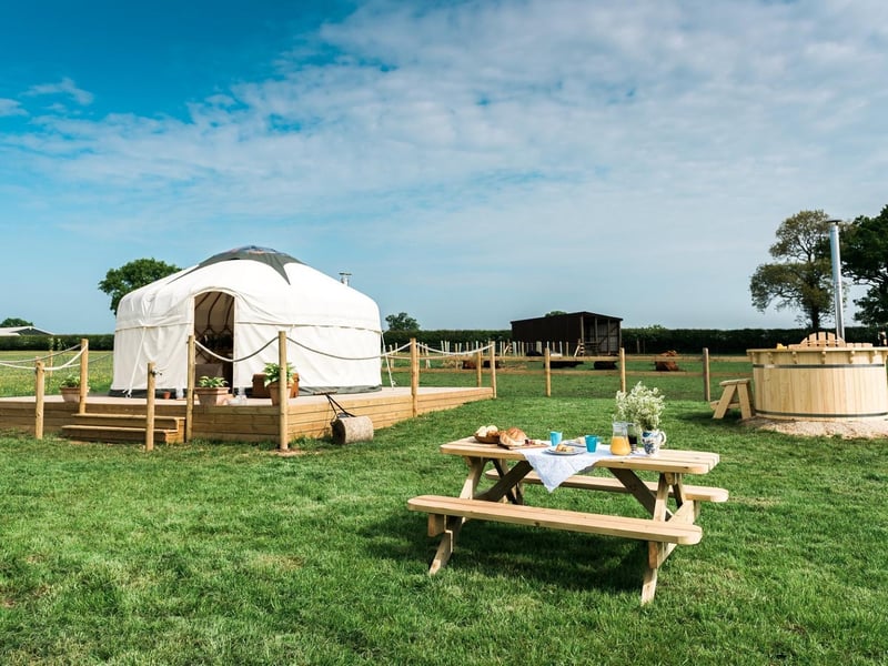 Nestled in Northamptonshire countryside near Silverstone you will find Jubilee Barn, a luxury boutique glamping site with a choice of offerings. From a British made yurt with crisp white linens, cow hide rugs and a calm natural aesthetics, set in the corner of a hay meadow. To a magically whimsical gypsy wagon tucked away surrounded by trees on the edge of a wheat field. Each glamping space has its own area of the farm, away from other people, and comes with en-suite bathrooms and log burning hot tubs, as well as a small log burner inside to keep
campers cosy and warm. Jubilee Barn offers the hire of bikes for the day or a pizza oven for the evenings, as well as hampers for breakfast, picnics and afternoon tea should you require it.