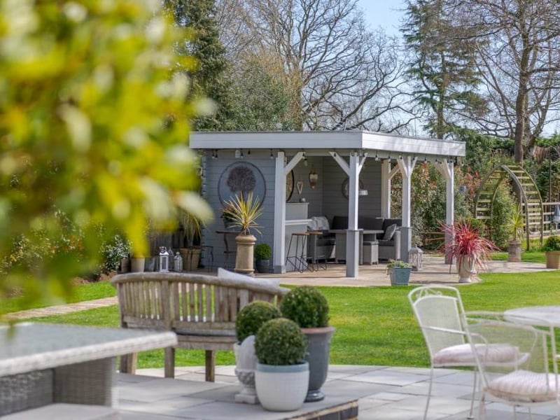 The garden features a summer house and outdoor kitchen complete with bar and television