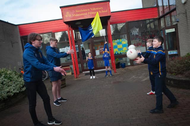 Steelstown past pupils Oran O'Kane and Cahir O'Doherty teaching hand passing skills to Riley and Aaron with Lucy and Aoife holding the banner made by Lucy's mum.