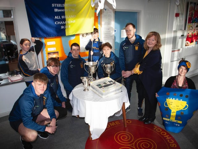 Cutting the celebration cake baked by McDaid's Bakery are, from left, Oran, Cahir, Eoghan, Donncha, Neil, Mrs Siobhan Gillen, Prinipal, Mrs O'Doherty, Mrs Gilmore and pupils Leo and Georgia holding the banner.