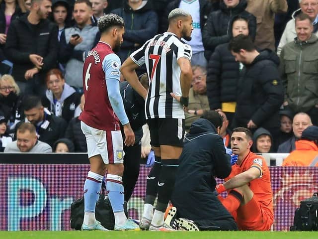 Aston Villa's Argentinian goalkeeper Emiliano Martinez (R) receives medical attention after suffering a knock during the English Premier League football match between Newcastle United and Aston Villa at St James' Park in Newcastle-upon-Tyne, north east England on October 29, 2022.  (Photo by LINDSEY PARNABY/AFP via Getty Images)