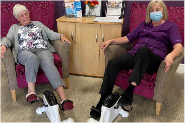 Palmersdene resident Elizabeth Lamb and care assistant Dawn Stewart using  floor pedals to take part in the cycling challenge.