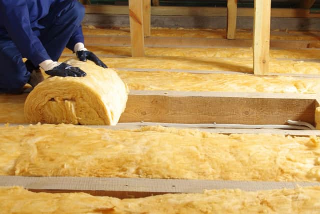 Construction worker thermally insulating house attic with glass wool 