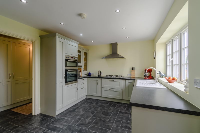 A spacious rear aspect kitchen with a range of wall and base units, modern integrated appliances.