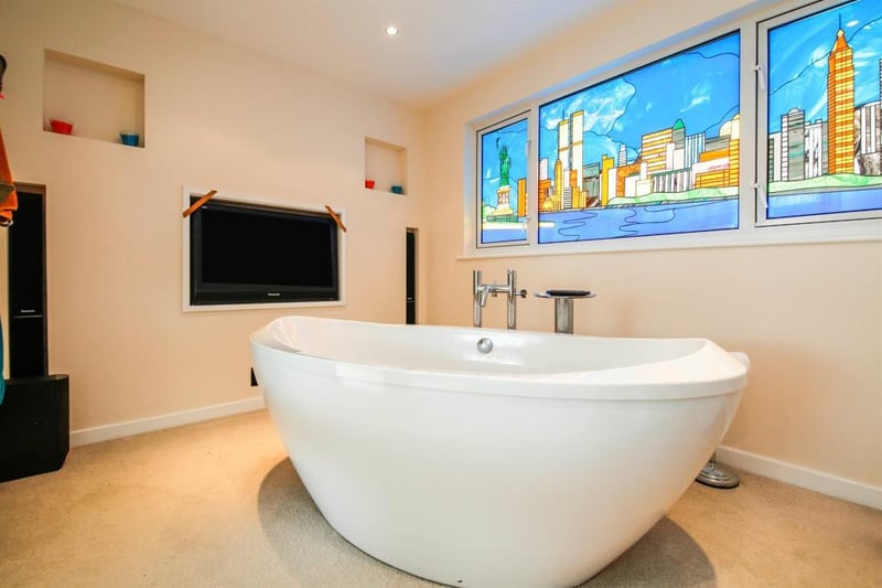 The stained glass and the TV add a luxurious touch to the bathroom.