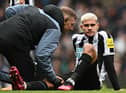 Newcastle United midfielder Bruno Guimaraes is treated by medical staff.