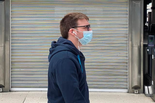 A pedestrian wearing a face mask or covering as a precautionary measure against spreading COVID-19, walks past a closed-down cafe (Photo by DANIEL LEAL-OLIVAS/AFP via Getty Images)