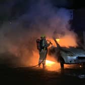 Firefighters attend the scene of a car fire.