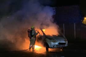 Firefighters attend the scene of a car fire.