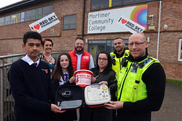 Mortimer Community College have raised funds for defibrillator. Front PC Darren Lough with pupil Theo Davis, 13 with Ashley pub landlady Cheryl Leighton, pupil Rive Bertram, 12, deputy head Joanne Thornton, Red Sky Foundation founder Sergio Petrucci and PCSO Steve Graham.