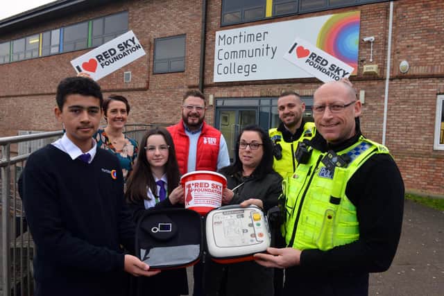 Mortimer Community College have raised funds for defibrillator. Front PC Darren Lough with pupil Theo Davis, 13 with Ashley pub landlady Cheryl Leighton, pupil Rive Bertram, 12, deputy head Joanne Thornton, Red Sky Foundation founder Sergio Petrucci and PCSO Steve Graham.