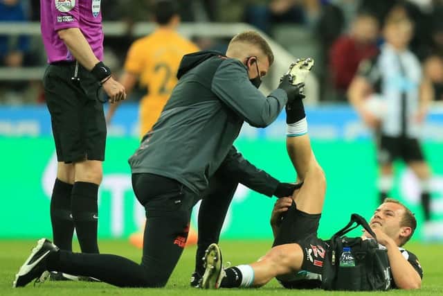 Newcastle United's Scottish midfielder Ryan Fraser (R) is treated for an injury during the English Premier League football match between Newcastle United and Wolverhampton Wanderers at St James' Park in Newcastle-upon-Tyne, north east England on April 8, 2022. (Photo by LINDSEY PARNABY/AFP via Getty Images)