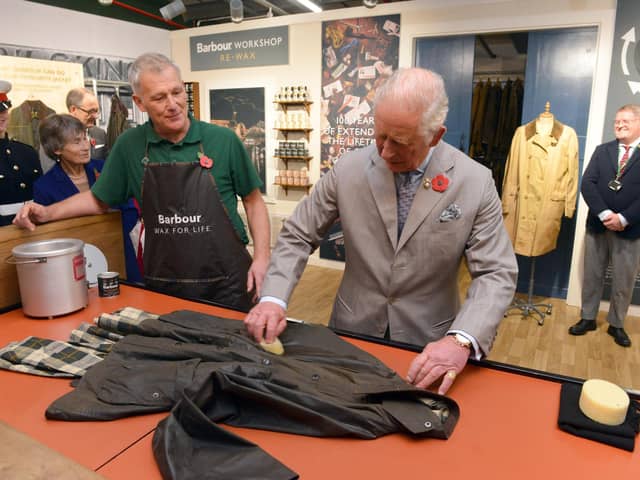 The Prince of Wales turns his hand to re-waxing a Barbour jacket.