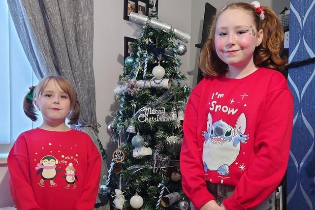 Sophie and Amelia pose for a festive photo by the tree for Christmas Jumper Day.