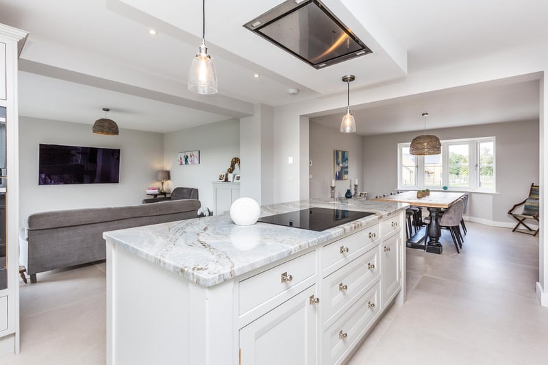 This stylish kitchen has integrated appliances, a central island with quartz worktop and breakfast bar and a large utility room