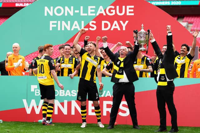 Hebburn Town's Michael Richardson (left), Hebburn Town's Louis Storey and chairman Vincent Pearson celebrate with players and staff with the Buildbase FA Vase 2019/20 trophy after victory in the Final at Wembley Stadium, London.