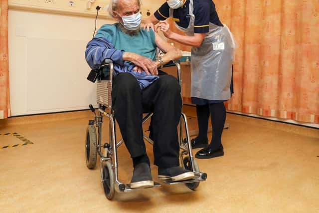 88-year-old Trevor Cowlett receives the Oxford University/AstraZeneca COVID-19 vaccine from nurse Sam Foster