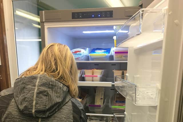 A volunteer helps to fill up the fridge.