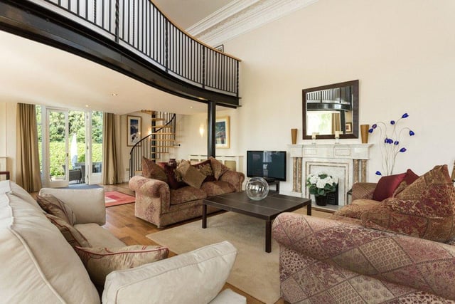 There are three reception rooms throughout the property, including this attractive drawing room with a marble fireplace at its heart and a spiral staircase which leads up to a spacious home office.
