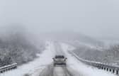 Car drives along snowy road.