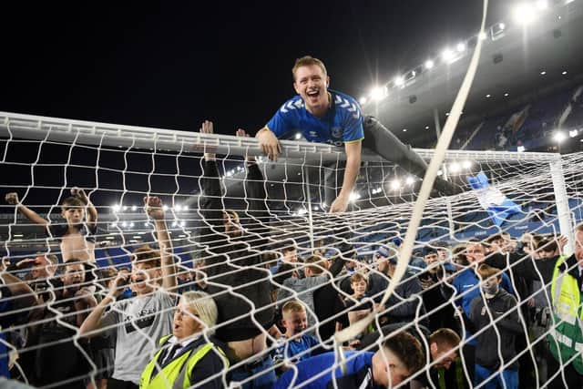 Everton fans celebrate on the pitch at Goodison Park.