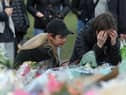 Women view floral tributes left at the band stand in Clapham Common, London, after clashes between police and crowds who gathered on Clapham Common on Saturday night to remember Sarah Everard. Serving police constable Wayne Couzens, 48, appeared in court on Saturday charged with kidnapping and murdering the 33-year-old marketing executive, who went missing while walking home from a friend's flat in south London on March 3. Picture date: Sunday March 14, 2021.