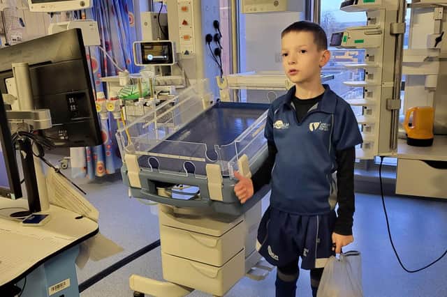 Jack is pictured next to the cot where he spent much of his time when he was a baby. He has a bag full of hearts to give to the nurses.