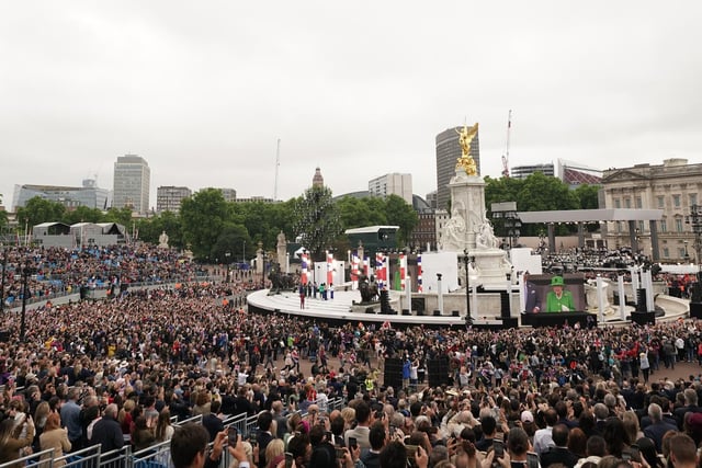The crowd watches the Queen on the balcony of Buckingham Palace