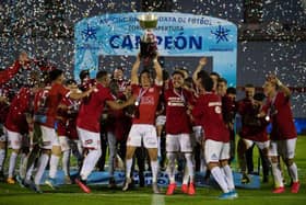 Rentistas' captain, Andres Rodales (C), holds up the trophy after winning Uruguay's Apertura tournament final football match against Nacional in Montevideo.