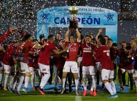 Rentistas' captain, Andres Rodales (C), holds up the trophy after winning Uruguay's Apertura tournament final football match against Nacional in Montevideo.
