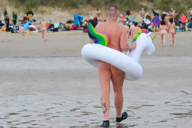 A skinny dipper entering the North Sea with his unicorn rubber ring.