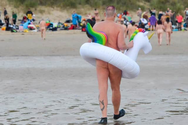 A skinny dipper entering the North Sea with his unicorn rubber ring.