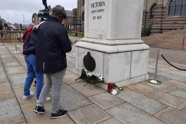 Examining the floral tributes left at the foot of the Queen Victoria memorial