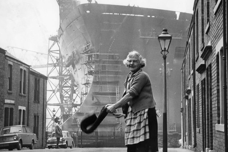 Daily chores being carried out in 1969 i the shadow of the tanker Esso Northumbria, which was to be launched on the Tyne by Princess Anne.
