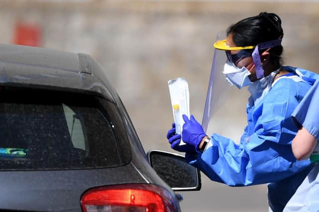 A medical worker explains to an essential worker about a testing kit for the novel coronavirus COVID-19 at a drive-in testing facility (Photo by DANIEL LEAL-OLIVAS/AFP via Getty Images)