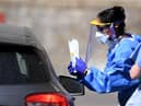 A medical worker explains to an essential worker about a testing kit for the novel coronavirus COVID-19 at a drive-in testing facility (Photo by DANIEL LEAL-OLIVAS/AFP via Getty Images)