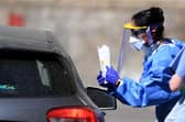 A medical worker explains to an essential worker about a testing kit for the novel coronavirus COVID-19 at a drive-in testing facility (Photo by DANIEL LEAL-OLIVAS/AFP via Getty Images)
