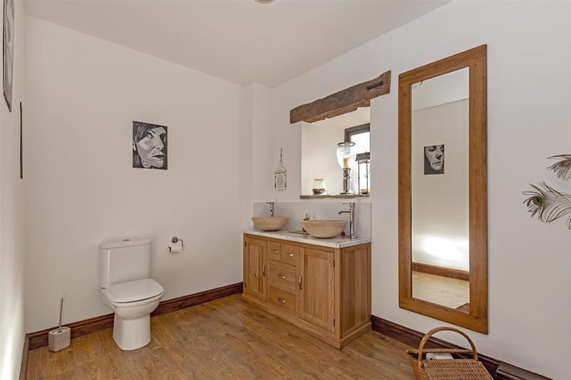 With twin, circular wash hand basin/pillar taps set within oak-style vanity unit. Low-level WC.