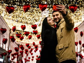 A couple poses for a selfie under heart-shaped balloons displayed for Valentine's Day in downtown Moscow on February 13, 2020. (Photo by Dimitar DILKOFF / AFP) (Photo by DIMITAR DILKOFF/AFP via Getty Images)