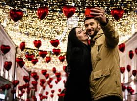 A couple poses for a selfie under heart-shaped balloons displayed for Valentine's Day in downtown Moscow on February 13, 2020. (Photo by Dimitar DILKOFF / AFP) (Photo by DIMITAR DILKOFF/AFP via Getty Images)