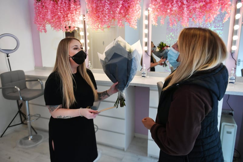 Ms McGarrell greets her first customer (who brings her flowers and a card) as her business reopens for the first time in months.