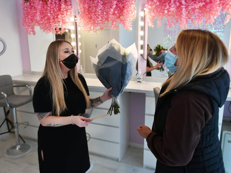 Ms McGarrell greets her first customer (who brings her flowers and a card) as her business reopens for the first time in months.