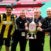 Hebburn Town manager Kevin Bolam (second right) celebrates with Angelos Eleftheriadis (left), coaches Michael Mulhern and Jason Miller (right) with the Buildbase FA Vase 2019/20 Trophy after victory in the Final at Wembley Stadium.