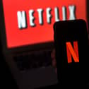 A computer screen and mobile phone display the Netflix logo. Photo by OLIVIER DOULIERY/AFP via Getty Images.