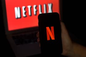 A computer screen and mobile phone display the Netflix logo. Photo by OLIVIER DOULIERY/AFP via Getty Images.