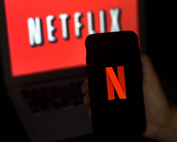 A computer screen and mobile phone display the Netflix logo. Photo by OLIVIER DOULIERY/AFP via Getty Images.