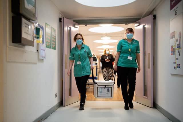 Pharmacists transport a cooler containing the Moderna vaccine, at the West Wales General Hospital in Carmarthen, the third vaccine to be approved for use in the UK, which is to be given to patients in Wales from Wednesday, April 7.